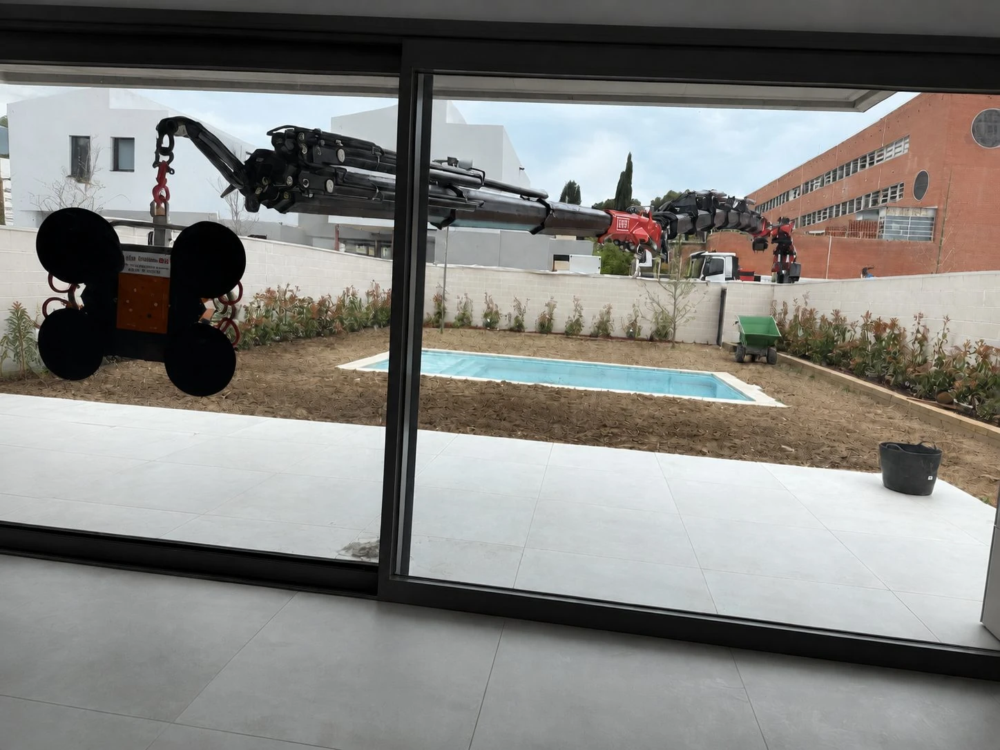Ventosa de vacío de la mini grúa de Solano entrando por el hueco de un ventanal, en una vivienda con piscina